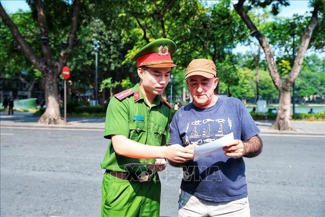 Cán bộ Công an giới thiệu cho một du khách nước ngoài tìm hiểu thông tin về Kiosk “Trạm Cảnh sát thông minh”, góp phần giúp người nước ngoài tiếp cận thuận tiện hơn với các dịch vụ hỗ trợ của lực lượng Công an. (Ảnh: Phạm Tuấn Anh/TTXVN)